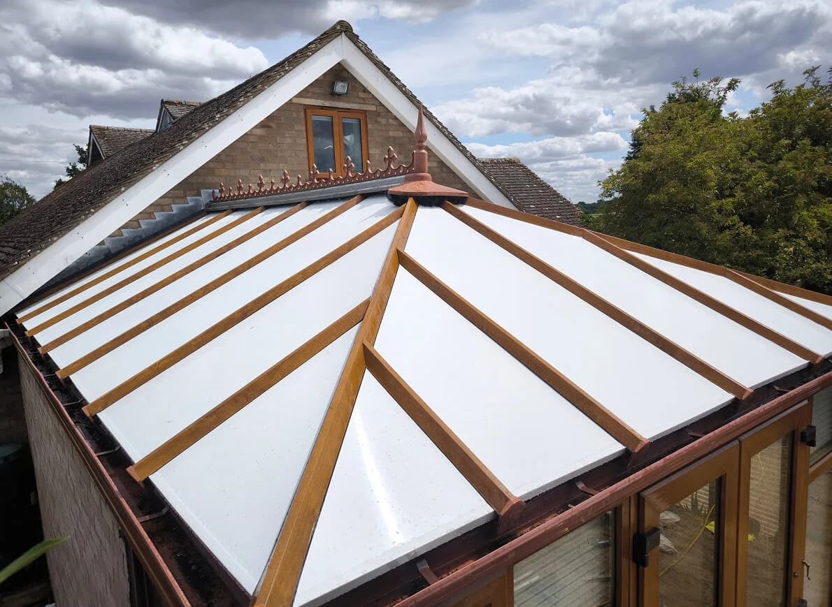 An insulated panel conservatory roof seen from above, close enough to read the joints between the composite panels and the glazing bars they sit in.