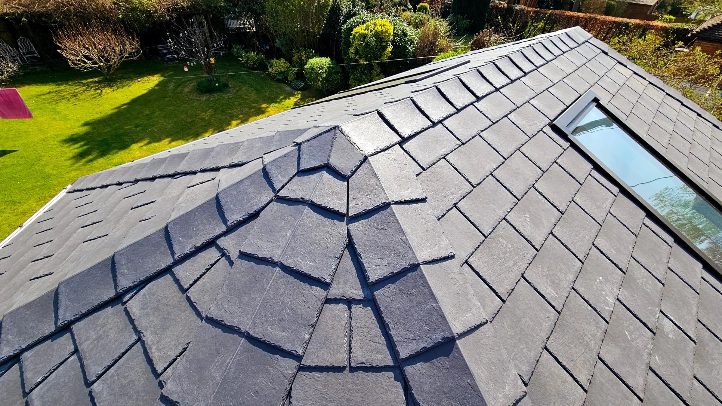 The tile courses and hip of a SupaLite lightweight tiled conservatory roof, near enough to read the slate-effect tiles.