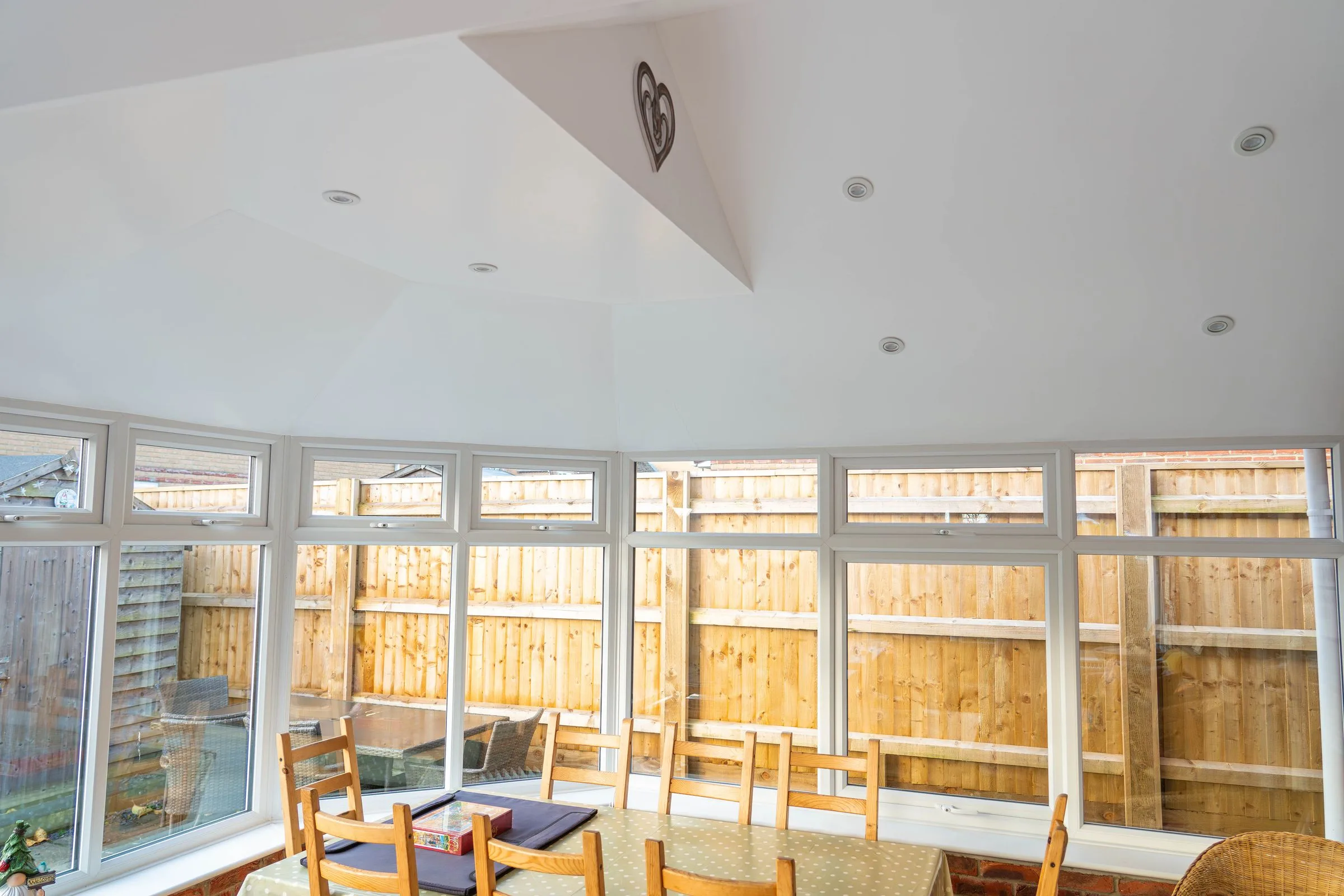 The plastered, sloping ceiling of a WarmerRoof insulated conservatory roof, with recessed spotlights, lit by daylight through the glazing.