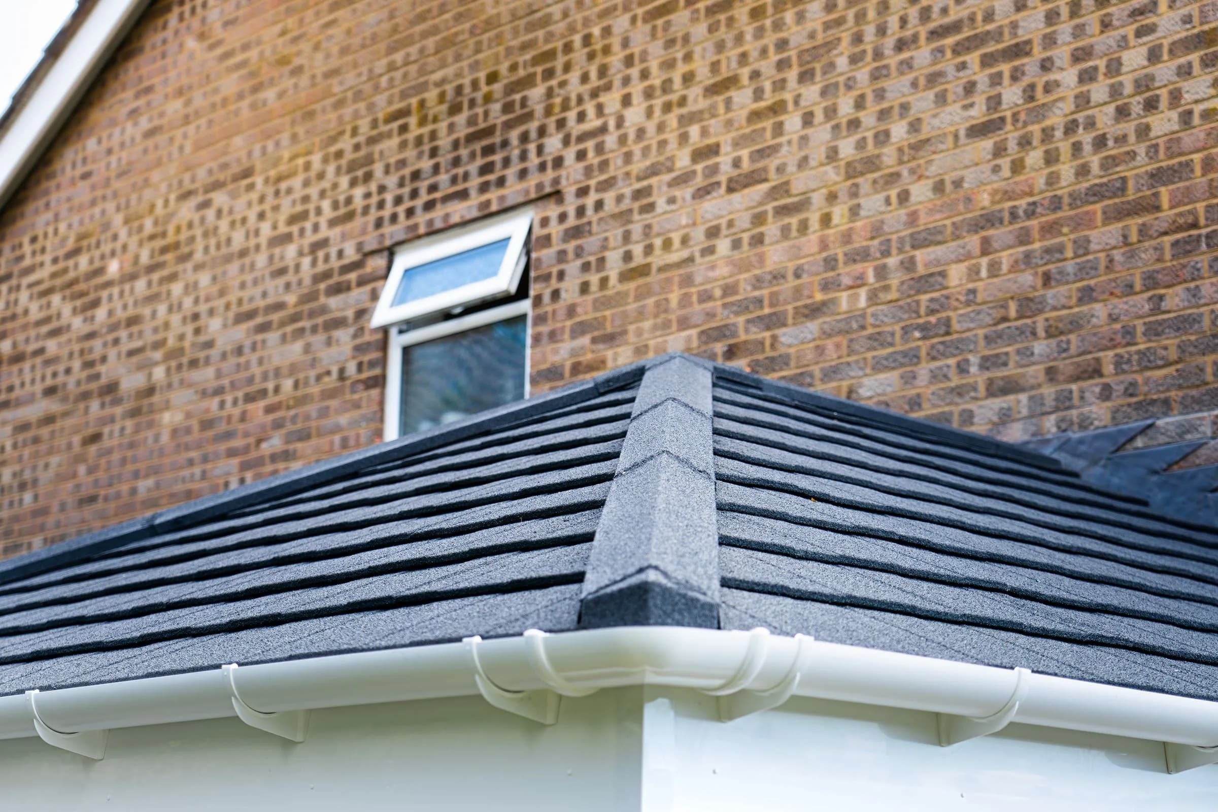 The tile courses and white eaves of a WarmerRoof conservatory roof in dark slate-effect tiles, close enough to read the tiles.