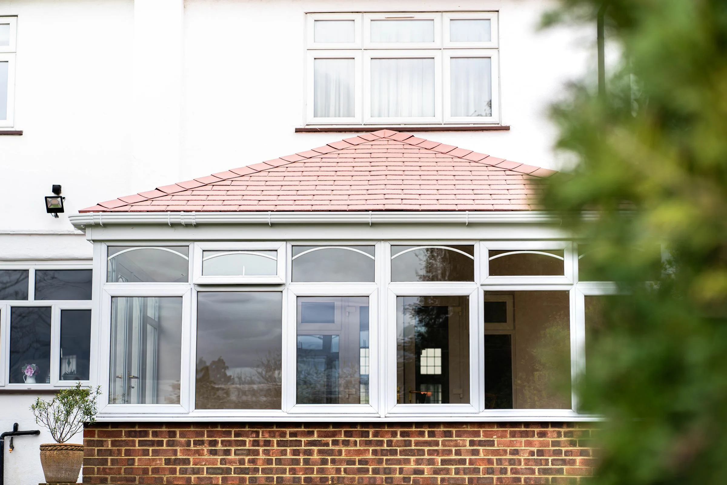 WarmerRoof tiled conservatory roof in terracotta tiles on a white conservatory, with the hip and ridge clearly visible.